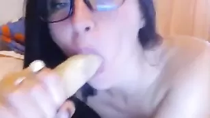 Очкастая брюнеточка эротично лижет дилдо